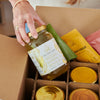 Bone broth detox featuring a hand holding a jar of vegan mineral broth elixir, packaged with other nutrient-rich blends in a box.